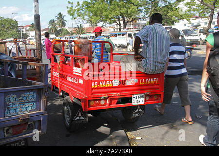 Arbeitnehmer um Anhänger am Taxistand sitzen auf einem Parkplatz mit Touristen zu Fuß durch, Stone Town, Sansibar, Stockfoto