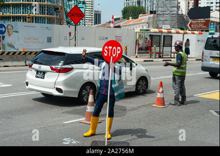 18.04.2018, Singapur, Singapur - Ein Arbeitnehmer nutzt ein stoppschild der Verkehr an einer Baustelle in Chinatown zu regulieren. 0 SL 180418 D 034 CAROEX.JPG [MODELL Stockfoto