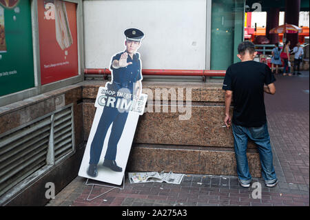 29.03.2019, Singapur, Singapur - ein Mann raucht eine Zigarette neben einem Karton Anzeige in Chinatown. 0 SL 190329 D007CAROEX.JPG [MODEL RELEASE: NEIN, PR Stockfoto