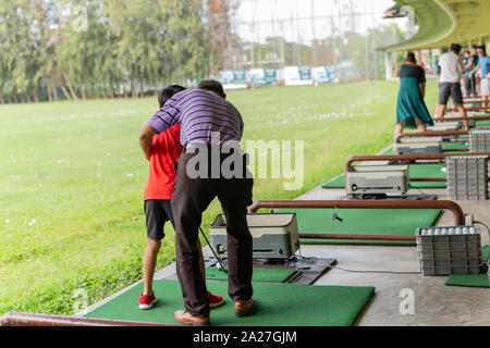 Personal Trainer, die Lektion zu Junge in Golf Driving Range. Stockfoto