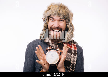 Es ist an der Zeit, bärtigen Mann mit einer kleinen Wecker, im Winter warme Kleidung. Stockfoto