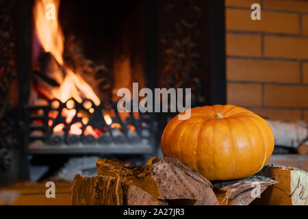 Halloween Kürbis liegt auf Birke. Im Hintergrund, Flammen aus dem Kamin. Mystische Urlaub Halloween. Jack o'Lantern. Stockfoto