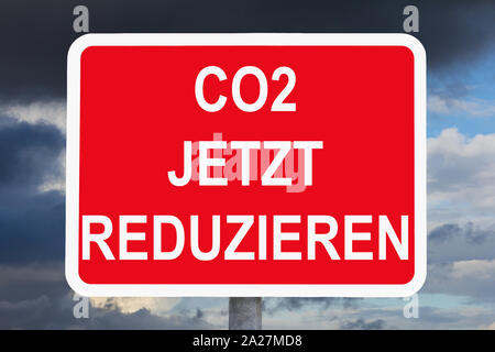 Klimawandel: CO2 JETZT REDUZIEREN Text auf roten und weißen Warnschild vor dunklen Himmel. Stockfoto