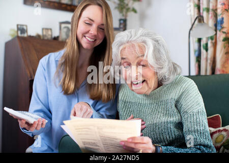 Frau helfen älteren Nachbarin mit Rechnungen und Unterlagen Stockfoto