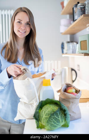 Portrait von Frau Heimweg von Shopping Trip Auspacken Lebensmittel in Kunststoff freien Beuteln Stockfoto