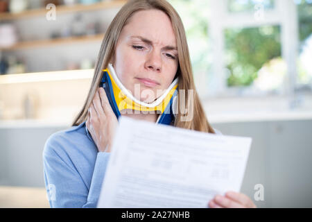 Frau zu Hause Lesen Schreiben nach Erhalt die Nackenschmerzen Stockfoto