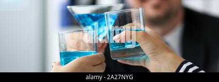 Die Kollegen im Büro feiern bedeutendes Ereignis mit blauen alkoholische Flüssigkeit im Glas Stockfoto