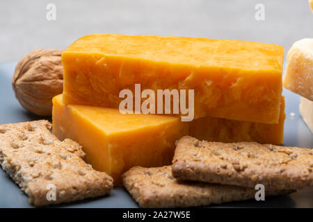 Käse Sammlung, gereift und orange original britischen Cheddar in Blöcke auf graue Platte serviert Nahaufnahme Stockfoto