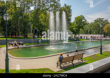 Charkow, Ukraine, August, 2019 Menschen laufen in einem Park, sitzen auf Bänken in der Nähe von Brunnen. Klar Sommertag. Frauen und Männer, Kinder und Erwachsene einen Rest Stockfoto