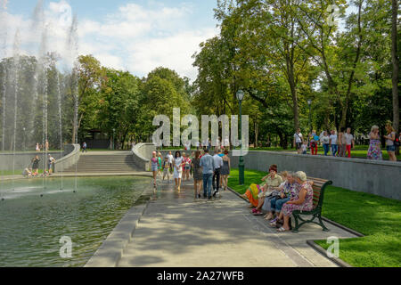 Charkow, Ukraine, August, 2019 Menschen laufen in einem Park, sitzen auf Bänken in der Nähe von Brunnen. Klar Sommertag. Frauen und Männer, Kinder und Erwachsene einen Rest Stockfoto