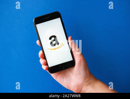 Kiew, Ukraine - Oktober 1, 2019: Studio geschossen von Hand mit Apple iPhone 8 mit Amazon auf einem Bildschirm Schriftzug. Auf einem blauen Hintergrund. Stockfoto