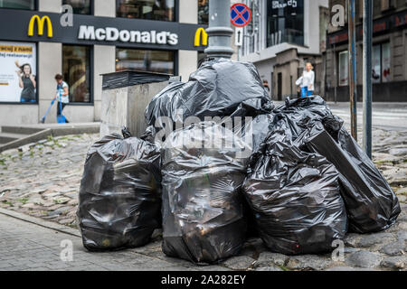 Stapel Plastiktüten voller Müll vor einem Fast Food Restaurant. Stockfoto