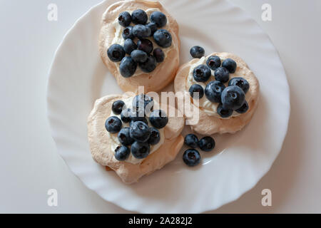 Pavlov Kuchen mit Sahne und frischen Blaubeeren auf einer weißen Platte Stockfoto