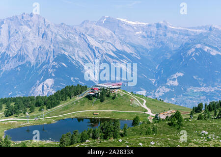 Blick auf den See mit einem nahe gelegenen Skilift im Sommer vor dem Hintergrund der Berge in den Alpen. Stockfoto