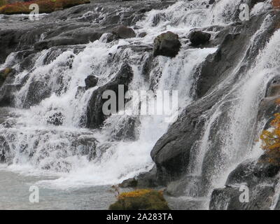 Tumbling Sturzbäche von Wasser über die vulkanischen Felsen an der Hraunfossar Wasserfälle, eine der dramatischen touristischen Destinationen in West Island. Stockfoto