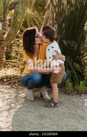 Voller Körper von Mutter bücken Vorschule im Alter von Sohn zu küssen. Stockfoto