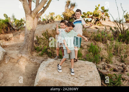 Drei junge Brüder tanzen auf Rock im sonnigen Kalifornien Kaktus Garten Stockfoto