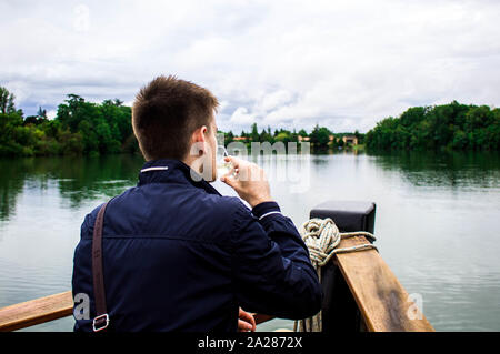 Ein Junge in einem Boot mit einem Drink mit einer schönen Landschaft Stockfoto