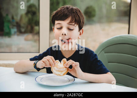 Porträt der jungen mit Creme Donut lecken Creme seine Wange Stockfoto