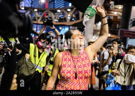 Hongkong, China. 1. Okt, 2019. Eine Dame spült ihr Gesicht mit einer Flasche Wasser, nachdem Sie Pfeffer in Causeway Bay, Hong Kong gesprüht. Heute ist der 70. Jahrestag der Gründung der Volksrepublik China. Statt Hong Kong am 1. Oktober markiert den 70. Jahrestag als "Tag der Trauer" und Aktivisten der Demokratiebewegung Zusammenstößen mit der Polizei in der Stadt. Credit: Keith Tsuji/ZUMA Draht/Alamy leben Nachrichten Stockfoto