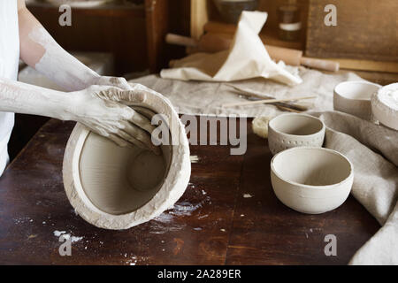 Weibliche Hände halten eine Schüssel für das Gießen von Ton-Produkte. Stockfoto