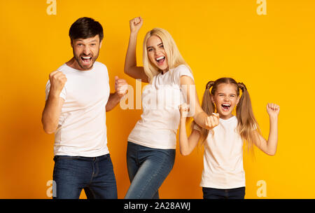 Familie aufgeregt Gestikulierend ja Schütteln Fäusten auf gelbem Hintergrund Stockfoto