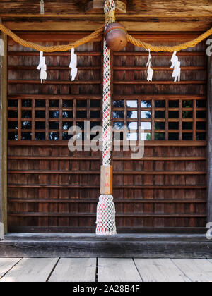 Close-up von Suzu (japanischen Shinto Bell) und das Seil unter der Traufe des Mitake Shinto Schrein hängen. Die Texte auf dem Seil bedeutet: Votive bietet. Stockfoto