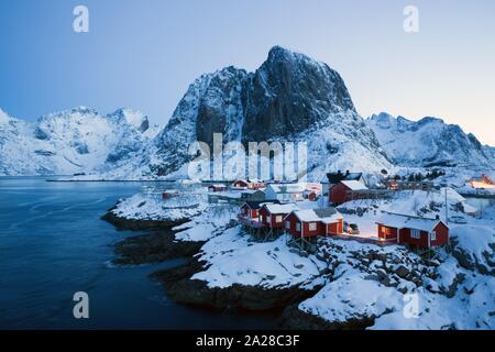 Traditionelle norwegische roten Holzhaus rorbu am Ufer auf den Fjord und die Berge in der Ferne zu stehen. Lofoten. Norwegen. World Travel Stockfoto