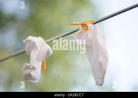 Weiße Socken sind auf einem Seil mit Wäscheklammern im Garten getrocknet Stockfoto