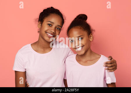 Süße kleine Schwestern umfassend über rosa Hintergrund Stockfoto