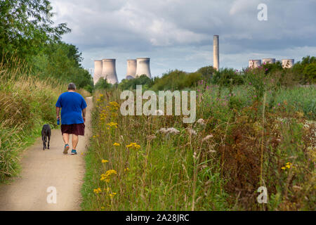 Übergewichtiger Mann in Shorts Spaziergänge sein Hund entlang der Trans Pennine Trail in Richtung Fiddlers Ferry Kraftwerk, St Helen's Canal, Gatewarth, Warrington Stockfoto