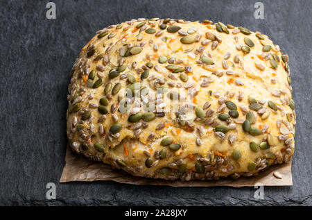 Saatgut fallenden Karotte Brot bloomer Laib auf schwarzen Stein Hintergrund Stockfoto