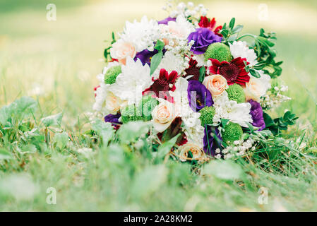 Ausschreibung wedding bouquet von violett, rosa und weißen Blüten liegen auf grünem Gras. Stockfoto