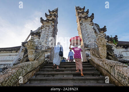 Unbekannter Mann und Frau mit Angebot im Temple Gate im Pura Penataran Agung Lempuyang Bali, Indonesien Stockfoto