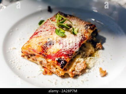 Lasagne mit Rindfleisch, Tomaten und Auberginen, gepudert mit Mozzarella. Restaurant mit. Lasagne auf weiße Platte. Stockfoto