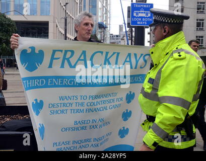 Ein anti fracking Demonstrant im Gespräch mit einem Polizisten vor dem Parteitag der Konservativen Partei, 2019 in Manchester, Großbritannien, am Tag 3. Die Gruppe sind kritische von Barclays Bank und seine angebliche Unterstützung für Fracking. Stockfoto