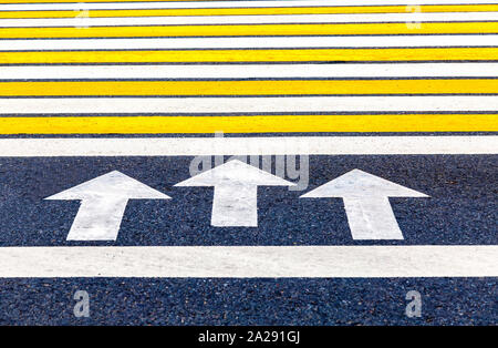 Fußgängerüberweg mit Pfeilen, weißen und gelben Streifen Nahaufnahme Stockfoto