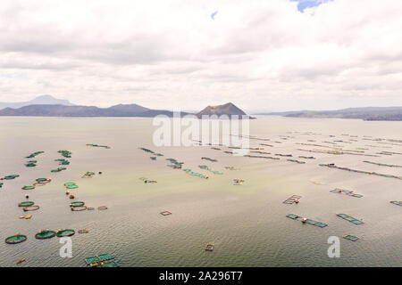 Lake Taal mit einem Vulkan und Fisch Käfigen auf eine Fischzucht, Ansicht von oben. Luzon, Philippinen tropischen Landschaft, Berge und Vulkan in den See. Stockfoto