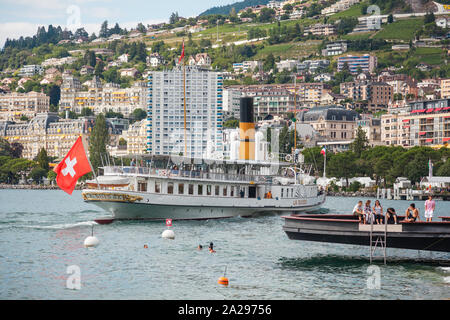 Die schönste Dampfschiff namens La Suisse mit Schweizer Flagge am Heck nähert sich Montreux Pier auf der Schweizer Riviera, Waadt, Schweiz winken Stockfoto