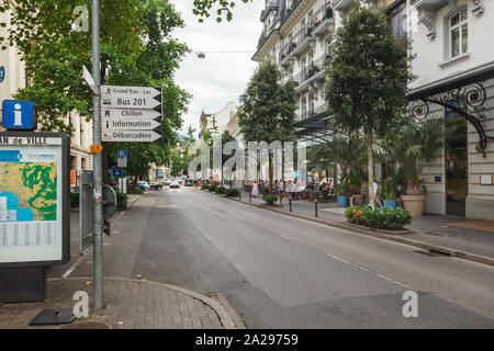 Blick auf die Avenue des Alpes vor Bahnhof mit Stadtplan und Wegweiser in Clarens, Waadt, Schweiz Stockfoto