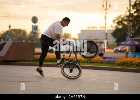 Der Kerl führt einen Stunt auf BMX, stehend auf das Hinterrad. Stockfoto