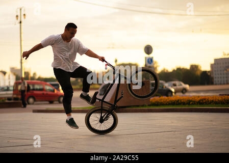 Der Kerl springt von der BMX, die auf dem Hinterrad steht. Stockfoto