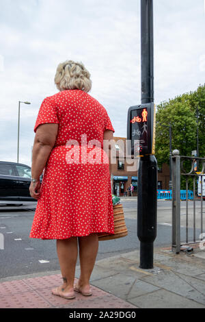 Eine Frau mittleren Alters warten auf ein grünes Licht an einer Ampel Stockfoto