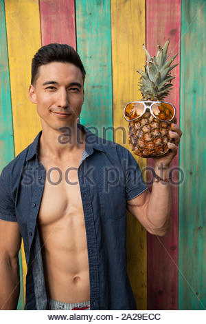 Portrait humorvoller junger Mann mit Ananas Sonnenbrille tragen im Sommer Terrasse