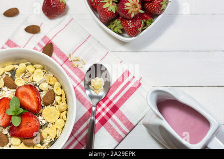 Schüssel mit Müsli, frische Erdbeeren, Mandeln und Joghurt auf weißem Holz- Tabelle, Ansicht von oben mit der Kopie. Gesunde Ernährung Konzept. Stockfoto