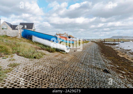 Kleine Boote bei Ebbe, Chesil Beach, Flotte Lagune, Dorset, Großbritannien. Stockfoto