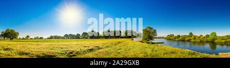 Landschaft im Sommer mit Bäumen, Wiesen, Fluss und Sonne Stockfoto