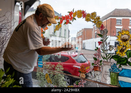 Ein Zeichen Schriftsteller Maler oder Künstler Malerei ein Design auf einem Blumenladen Fenster Stockfoto