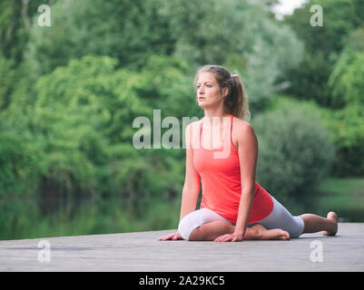 Frau in den 30er Jahren Yoga im Park auf einem Pier Stockfoto