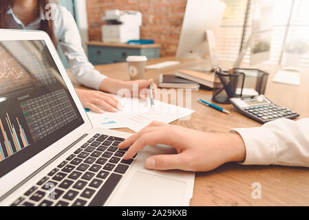 Investoren arbeiten im Büro. Finanzberater mit Laptop und Grafik auf dem Bildschirm. Frau zeigt auf Anweisung Stockfoto